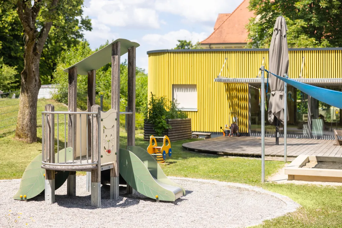 Gebäude und Garten der Kita St. Mauritius in Obermeitingen, umgeben von grünen Rasenflächen und fröhlichen Spielzeugen