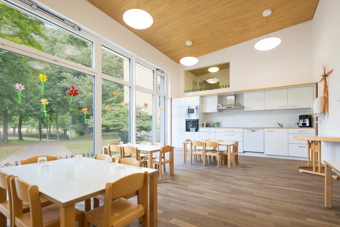 Esszimmer der Kindertageseinrichtung mit heller Küche und vielen Sitzgelegenheiten für die Kinder