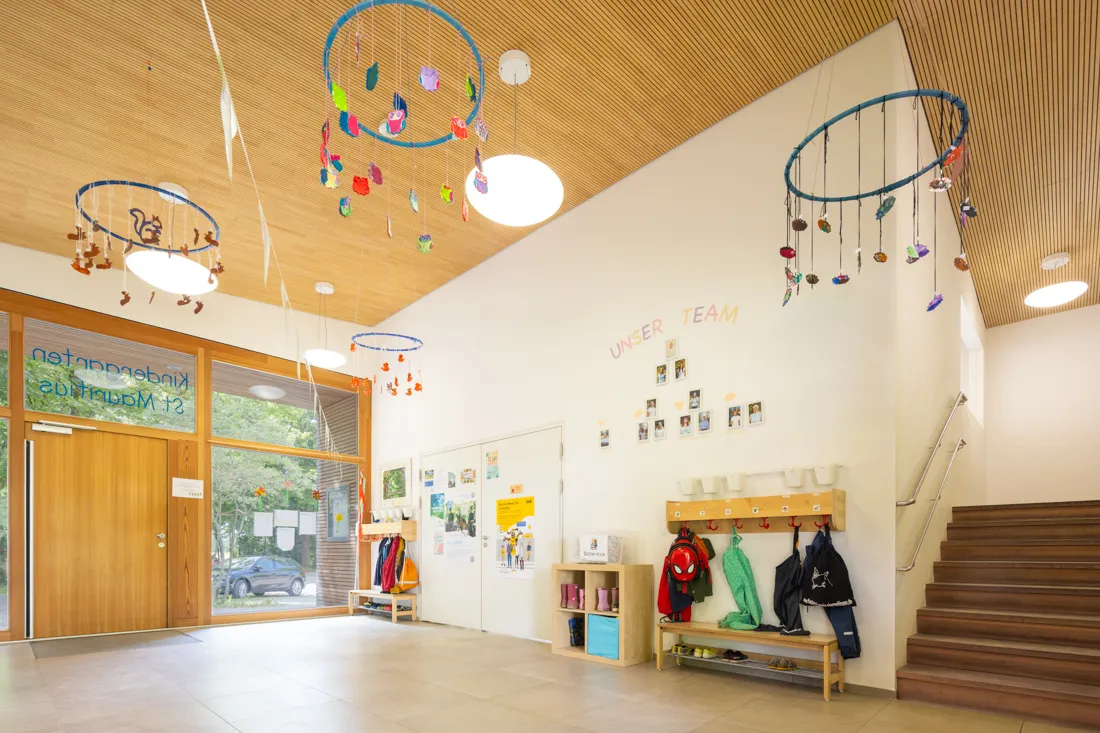 Einladender Eingangsbereich der St. Mauritius Kindertagesstätte mit Garderobe, bunten Basteleien und großen Fenstern